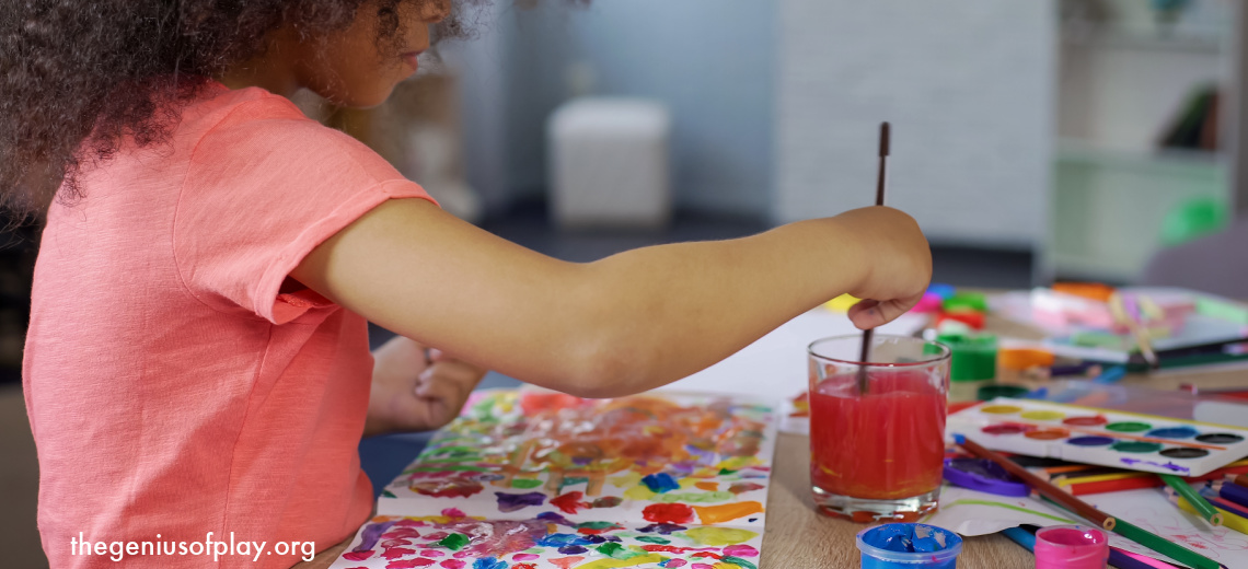 young African American pre-school girl using a paint brush and watercolor paints to paint a colorful picture