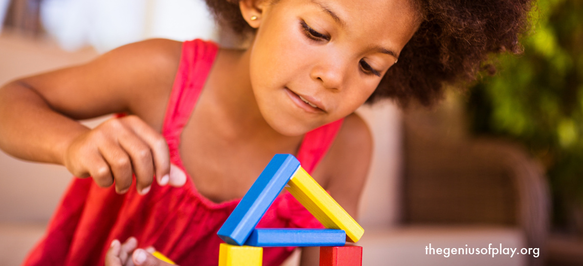 Young African American girl intently playing with colorful wooden blocks