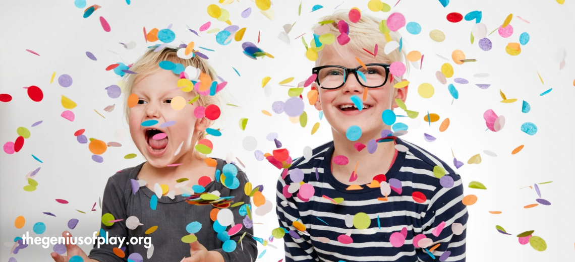two young children smiling as festive confetti falls down around them