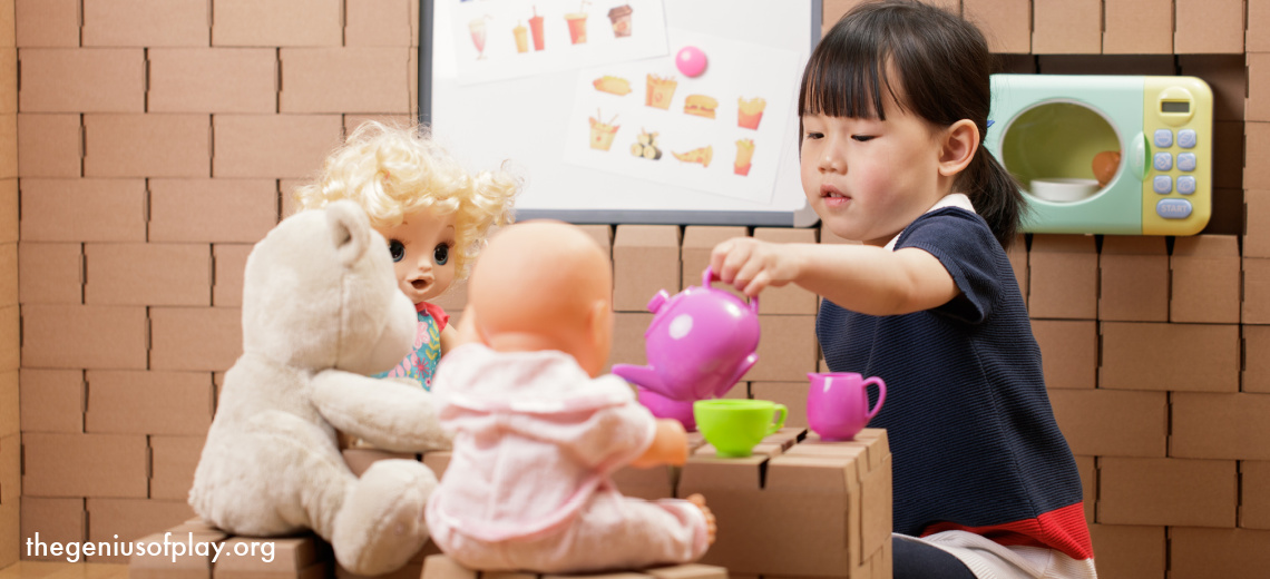Asian American toddler girl having a pretend tea party with her dolls and stuffed animals