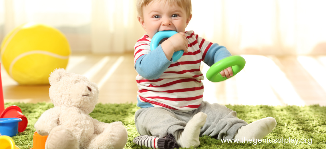 young baby boy with toy plastic rings in his mouth 