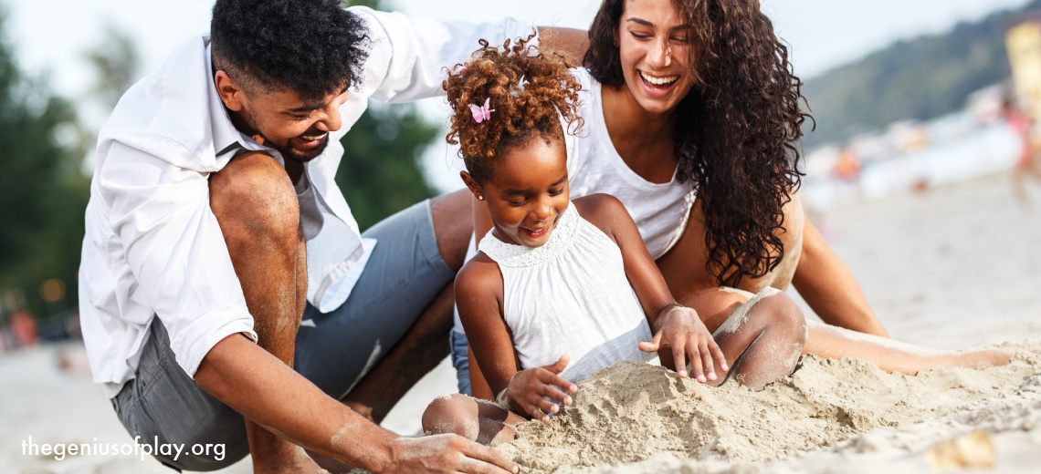 young mixed race family sitting in the sand on a beach on a summer day