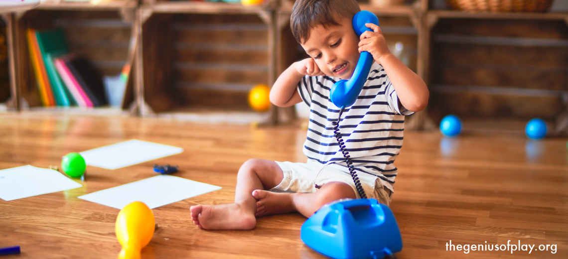 young pre-school boy talking on a play telephone