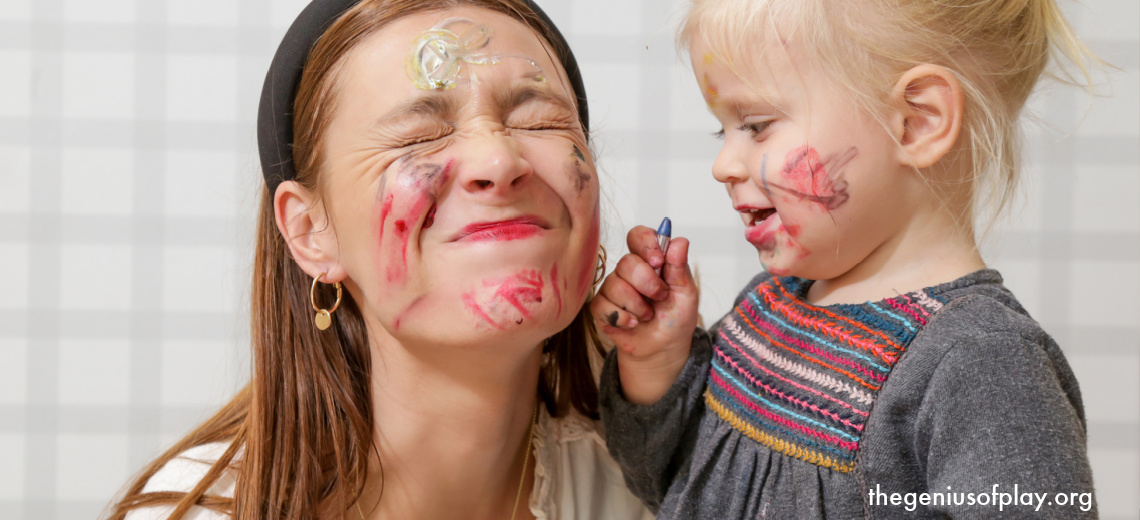 toddler girl using crayons to color on her mom’s face