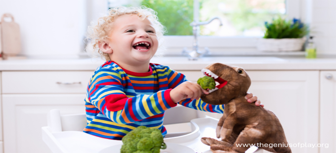Young child feeding broccoli to a toy dinosaur