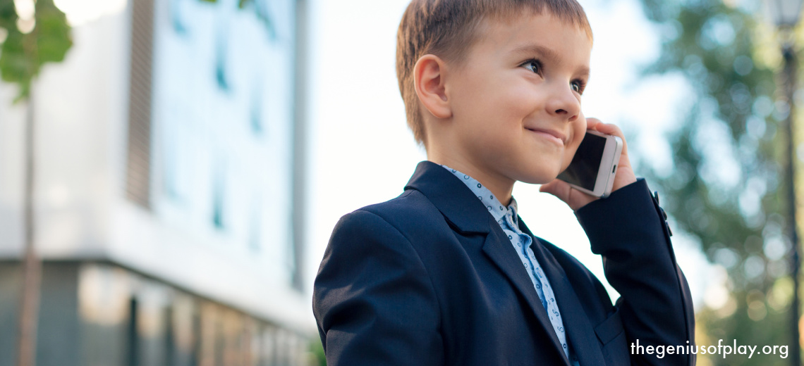 young Caucasian boy dressed up in a suit talking on a cell phone pretending to go to work