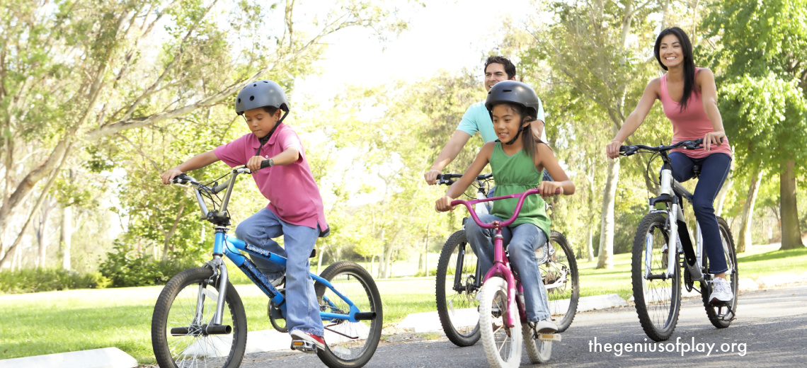Latino family of four wearing helmets while riding bicycles outdoors