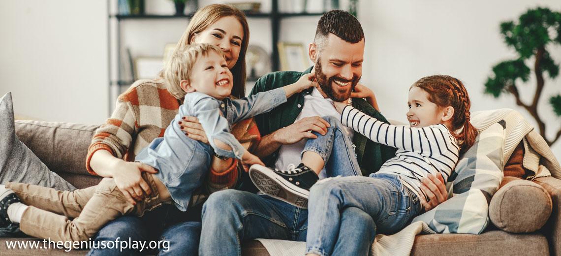 happy family with mother, father and kids playing on the couch at home